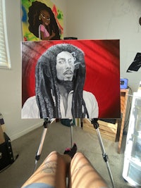 a painting of bob marley with dreadlocks on a easel