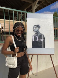 a woman standing next to a painting of dior