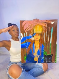 a woman holding up a painting of a woman in a hat